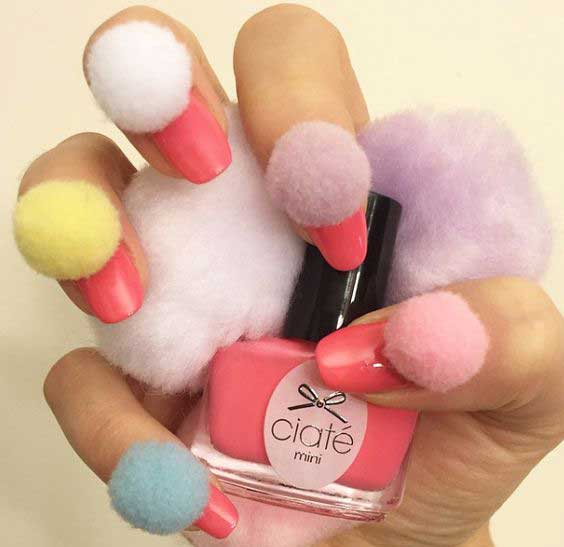 Fluffy pom-poms adorn the manicure